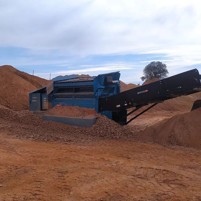 Una máquina azul está sentada encima de una pila de tierra.