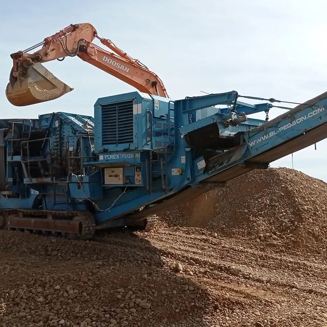 Una excavadora Doosan está cavando en un montón de tierra.