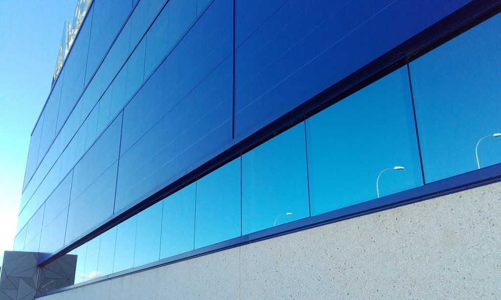 Un edificio azul con muchas ventanas y un cielo azul al fondo.
