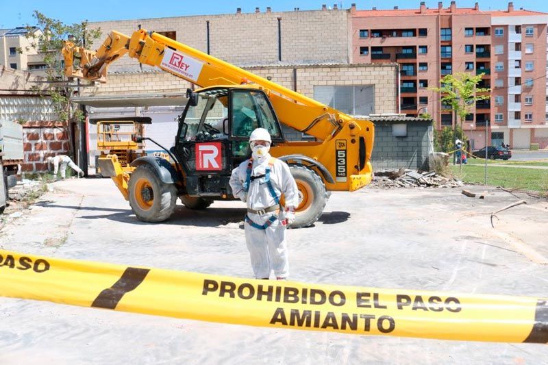 Un hombre parado frente a una cinta amarilla que dice prohibido el paso amianto