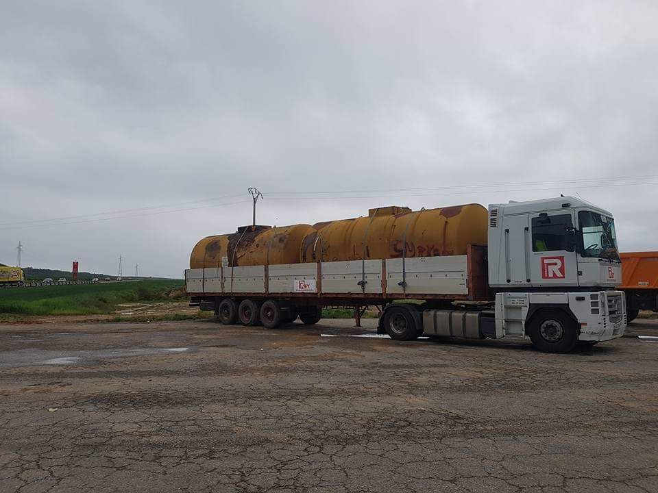 Un camión blanco con la letra r en el costado está estacionado en un estacionamiento.