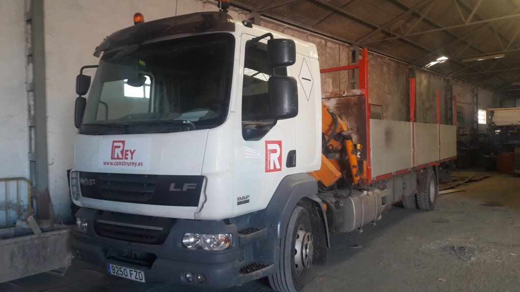 Un camión blanco con una grúa en la parte trasera está estacionado en un almacén.