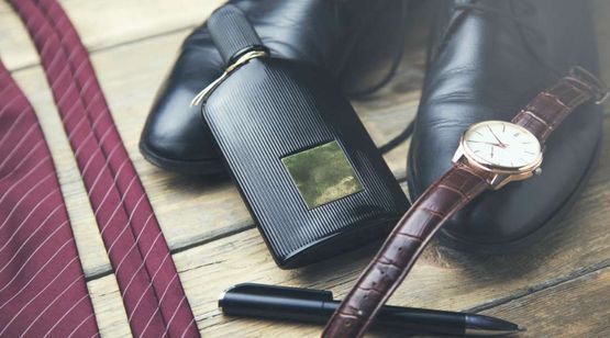 Un par de zapatos, un reloj, un bolígrafo y una billetera están sobre una mesa de madera.