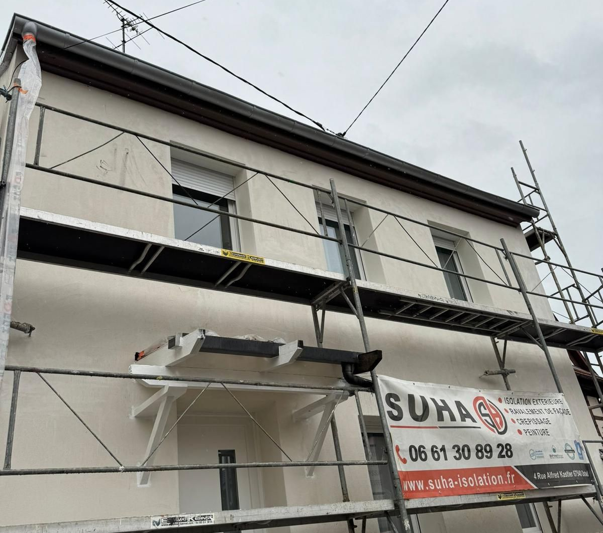 Bâtiment blanc avec porche ouvert à poutres apparentes.