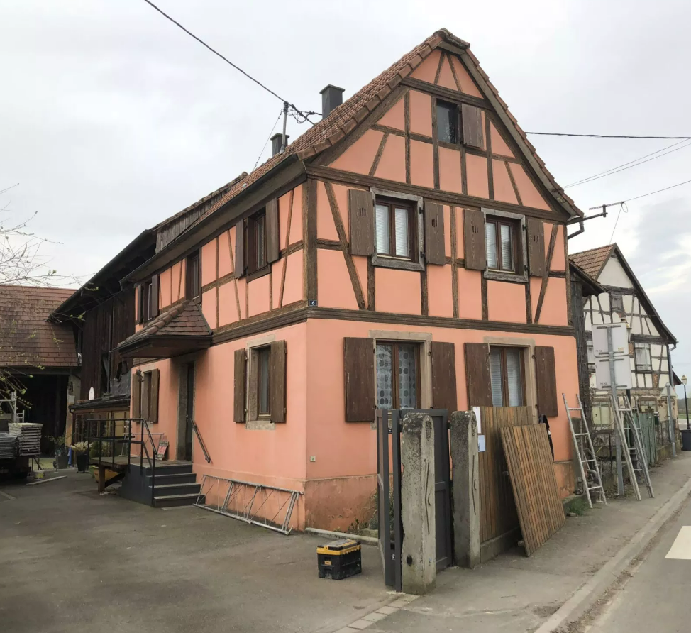 Maison en rénovation avec échafaudages, façade jaune pâle et toit foncé.