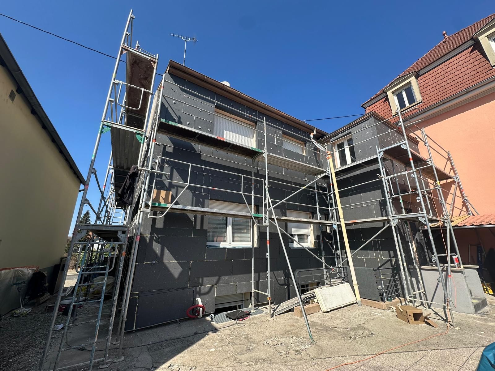 Construction d'un immeuble moderne avec des balcons blancs en saillie ; une plateforme d'ascenseur est en service.