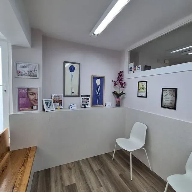 Una sala de espera con dos sillas y un mostrador en un consultorio dental.