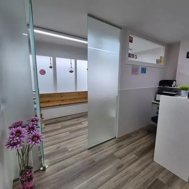 Una habitación con una puerta corrediza de vidrio y flores en un jarrón.