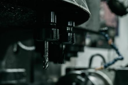 Primer plano de una herramienta de mecanizado con una broca de corte; entorno industrial.