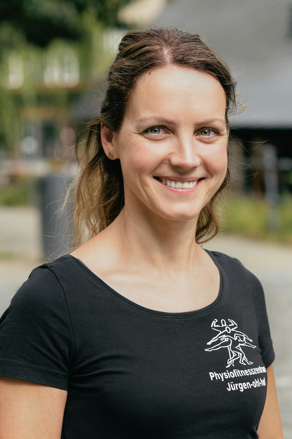 Lächelnde Frau im Freien in einem schwarzen T-Shirt vor verschwommenem Hintergrund