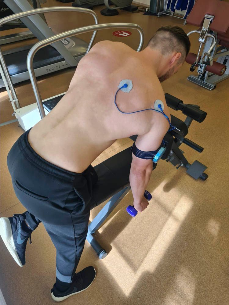 Eine Person, die in einem Fitnessstudio an einer Kabelzugmaschine Armübungen macht