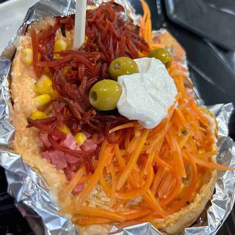 Sándwich abierto con zanahorias ralladas, carne, maíz, aceitunas y crema envuelto en papel de aluminio.