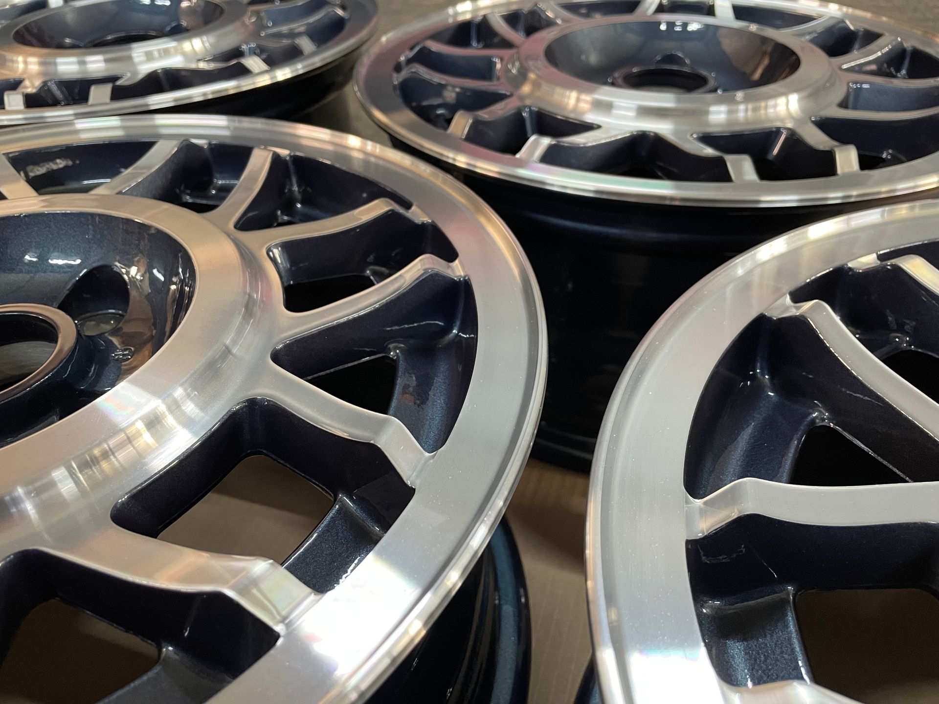 Vier Leichtmetallfelgen, dunkelblau mit silbernen Felgenrändern, Nahaufnahme aus einem bestimmten Winkel.