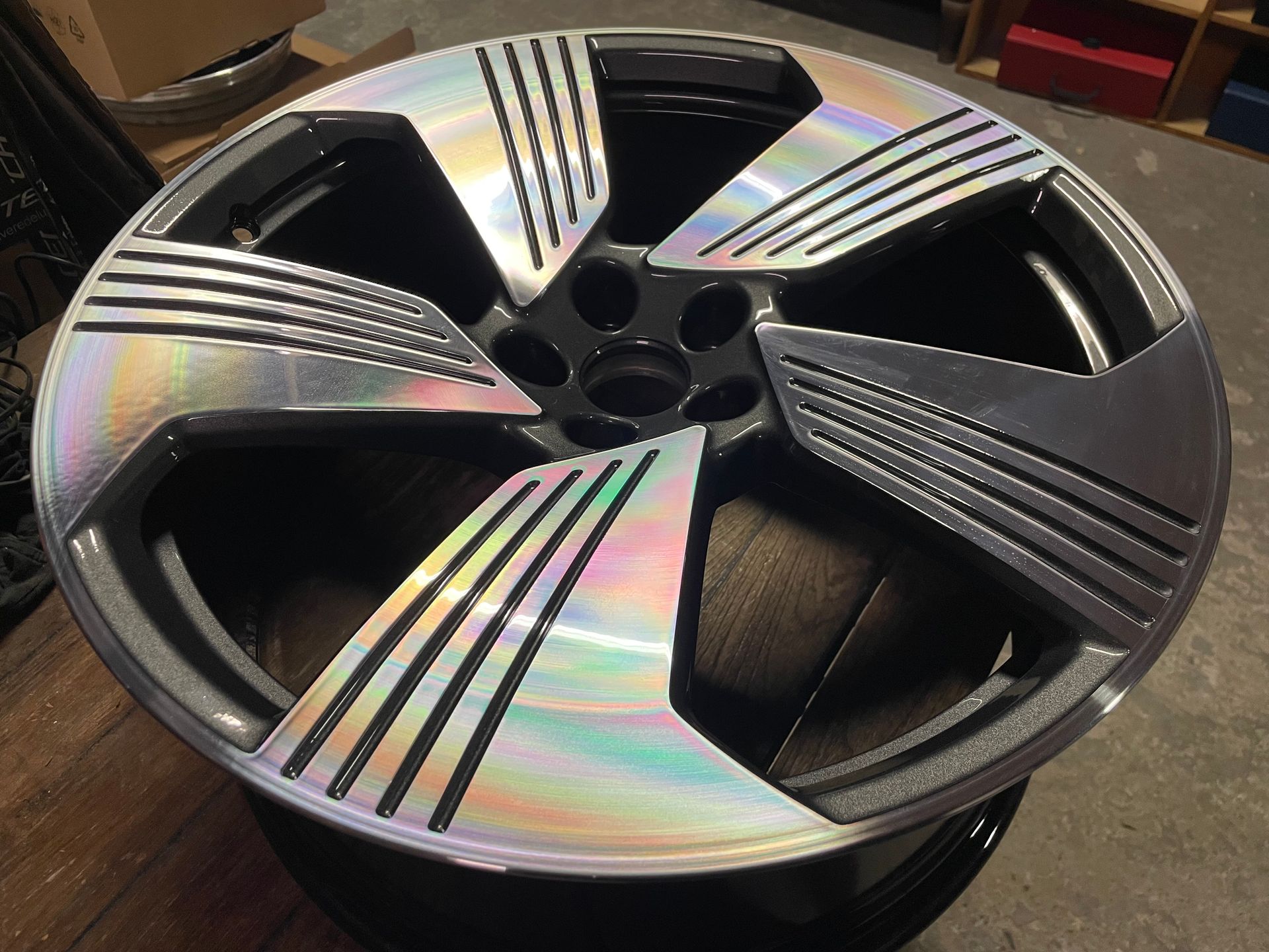 Nahaufnahme eines holografischen Autorades mit schwarzen und silbernen Details, das auf einer schwarzen Oberfläche ruht.