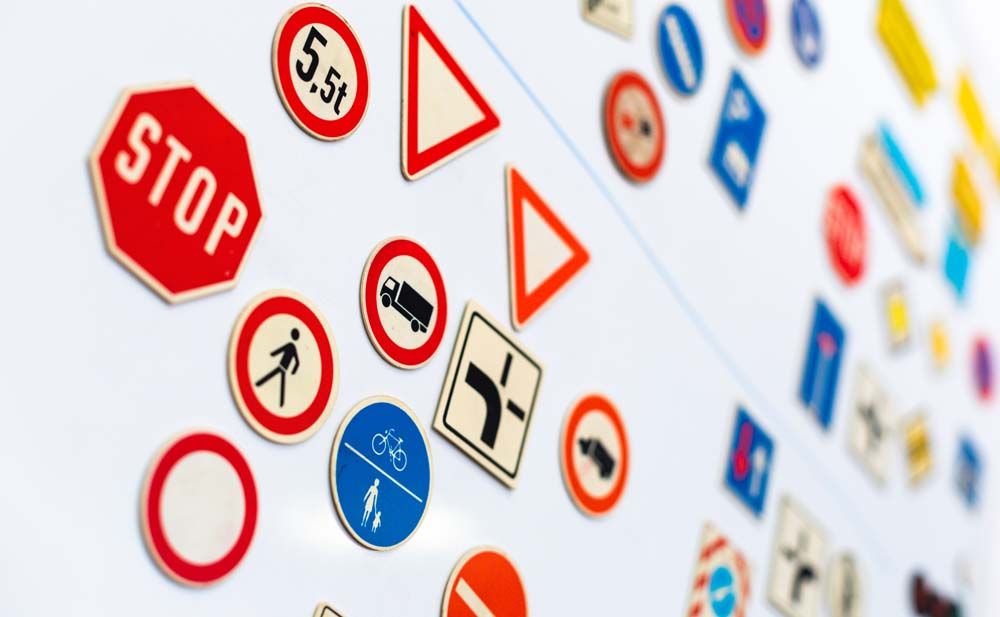 Sammlung bunter Miniatur-Verkehrszeichen auf weißem Grund, darunter Stopp- und Vorfahrtsschilder.