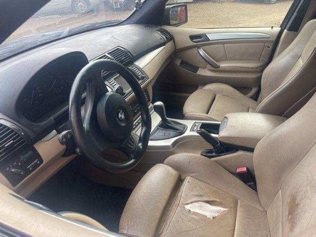 Interior de coche de cuero color canela con volante, salpicadero y asiento del conductor desgastados.