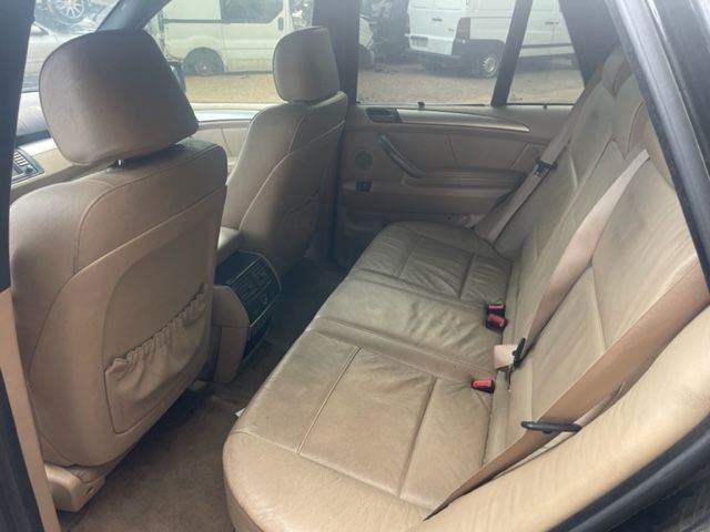 Interior color beige del asiento trasero de un coche con el respaldo plegado y los asientos delanteros visibles.