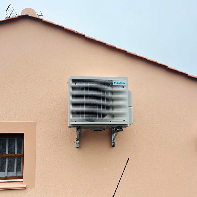 PAC Pompe à chaleur installée en hauteur sur un mur extérieur d'une maison d'habitation par FIEVRE Frères climatisation.