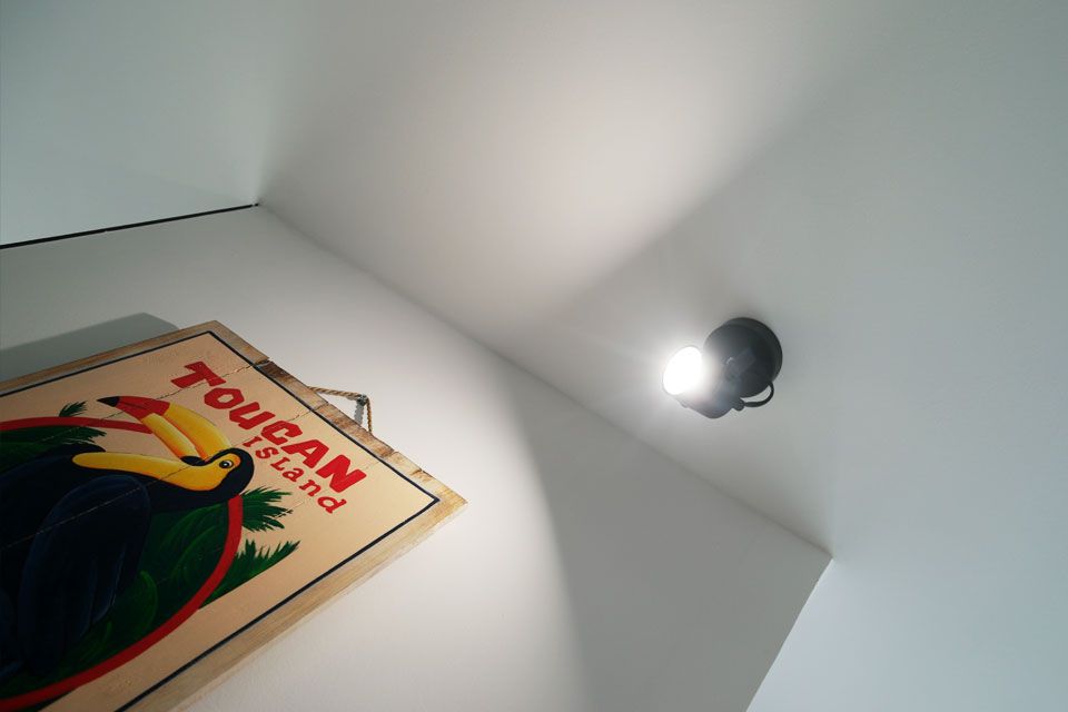 Spot électrique au plafond soulignant une oeuvre par son éclairage