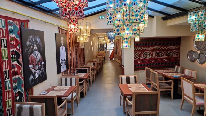 Intérieur de restaurant avec tables, chaises, lampes colorées et textiles traditionnels.