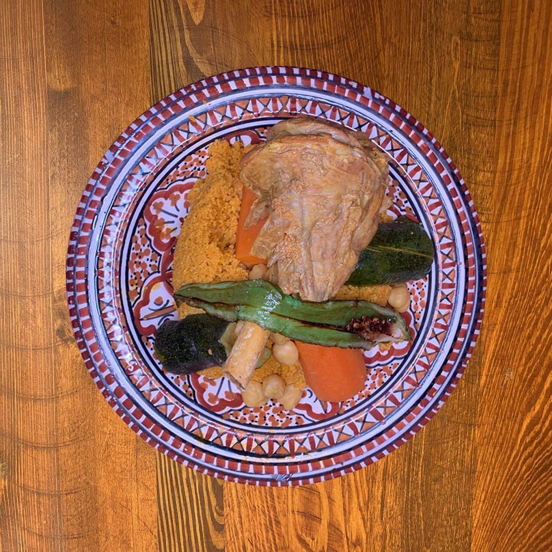 Tajine tunisien au poulet, légumes et couscous, servi sur une assiette à motifs.
