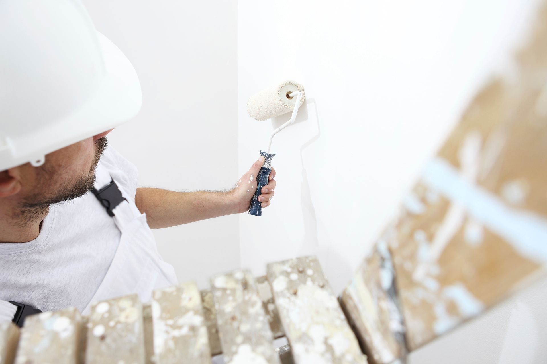 Un hombre está pintando una pared con un rodillo de pintura.