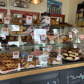 Bakery display case with various baked goods; rolls, pastries, and bread.