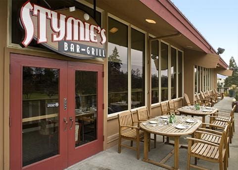 Stymie's Bar-Grill exterior with red doors, outdoor seating, and large windows.