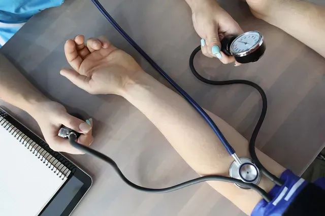 Um profissional de saúde utiliza um medidor de pressão arterial e um estetoscópio para medir a pressão arterial 