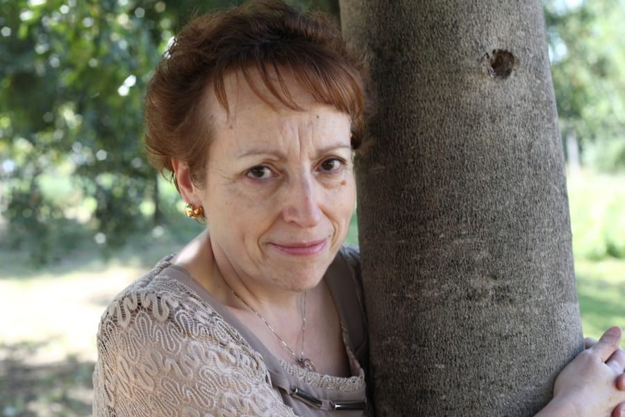 Una mujer está apoyada contra un árbol en un parque.