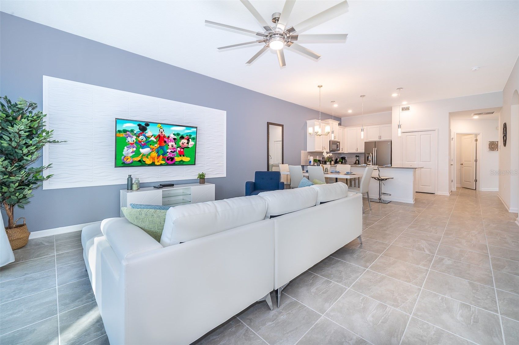 A living room with a white couch and a flat screen tv on the wall.
