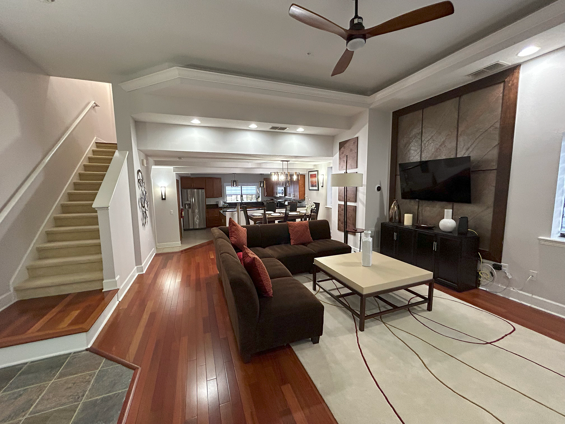A living room with a couch , coffee table , television and stairs.