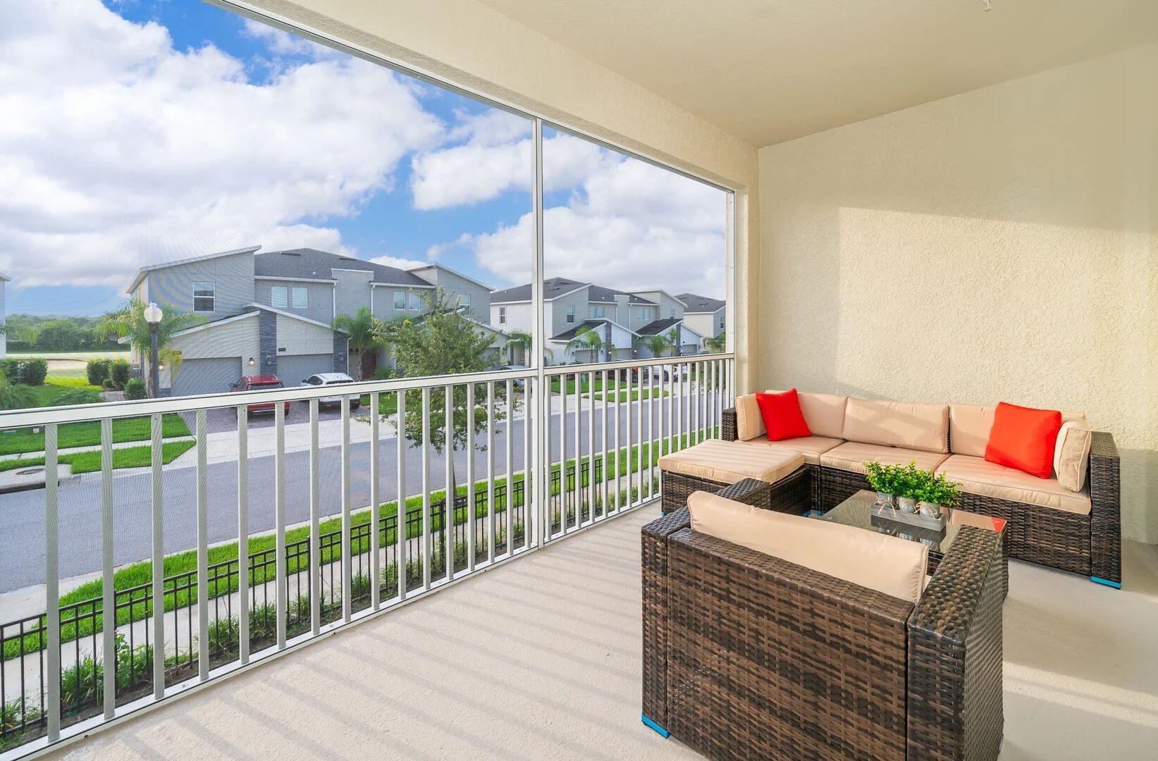 A balcony with wicker furniture and a view of a residential area.