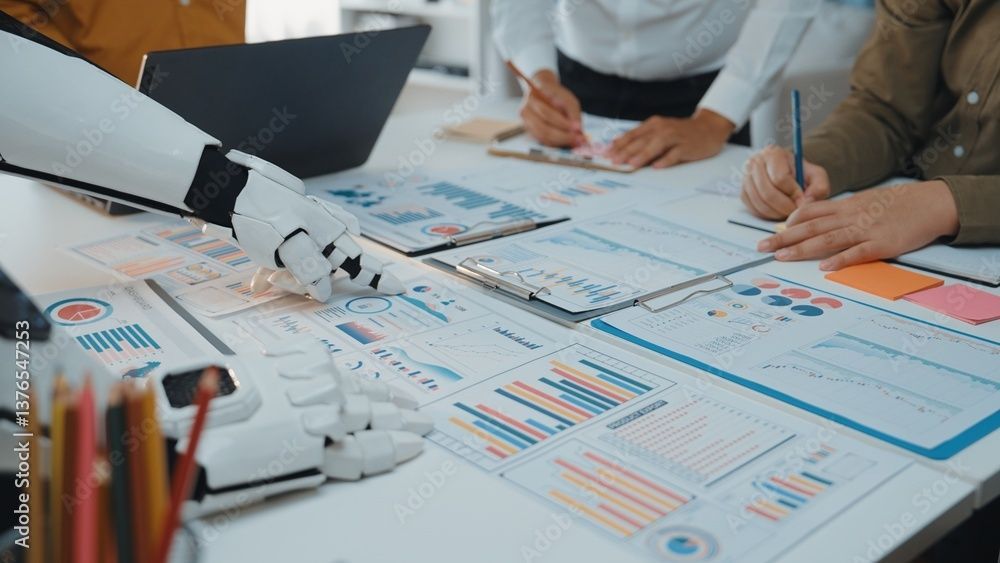 Un bras robotisé pointe vers des graphiques et des tableaux sur une table pendant que des personnes travaillent avec des données.