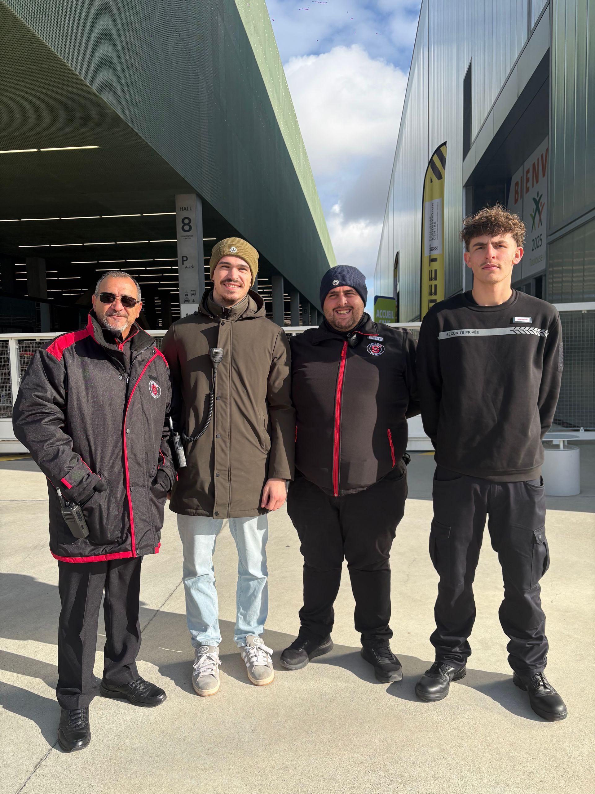 Brassard orange sur le bras d'un agent de sécurité, avec en fond une voiture blanche floue.