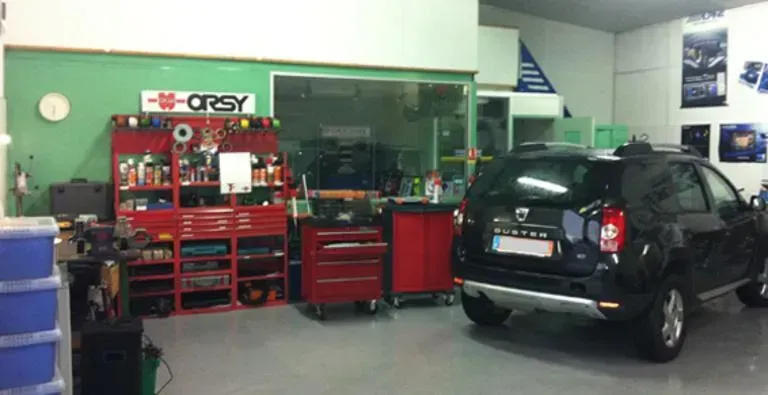 Photo d'un atelier avec les outils et un véhicule noir.