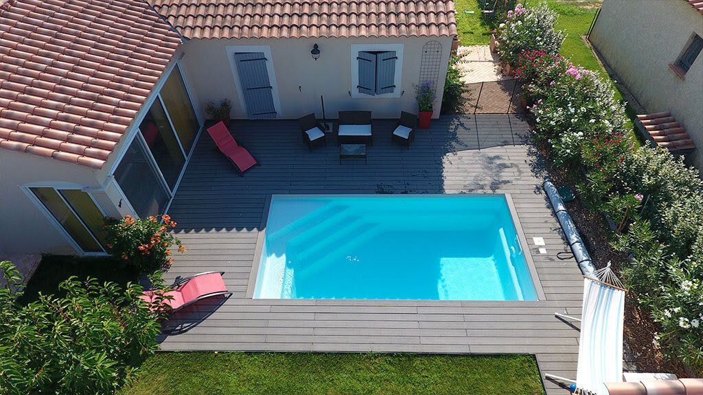Une maison avec une terrasse et une piscine et des transats