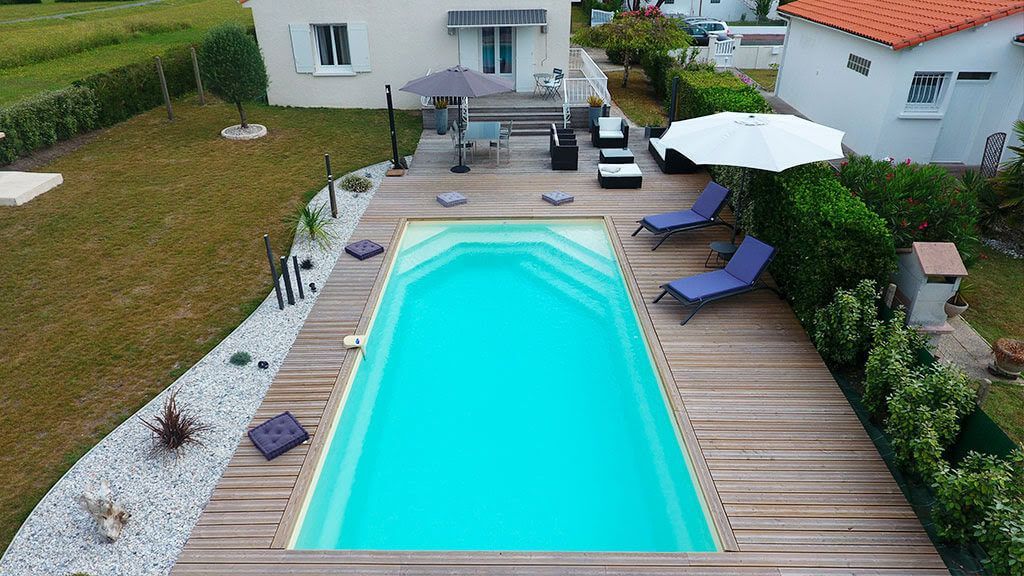 Une terrasse avec une piscine, des transats et des parasols