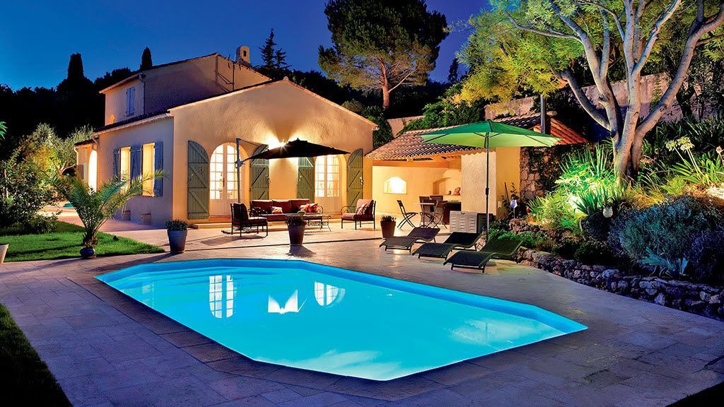 Une maison avec des lumières qui éclairent une piscine creusée