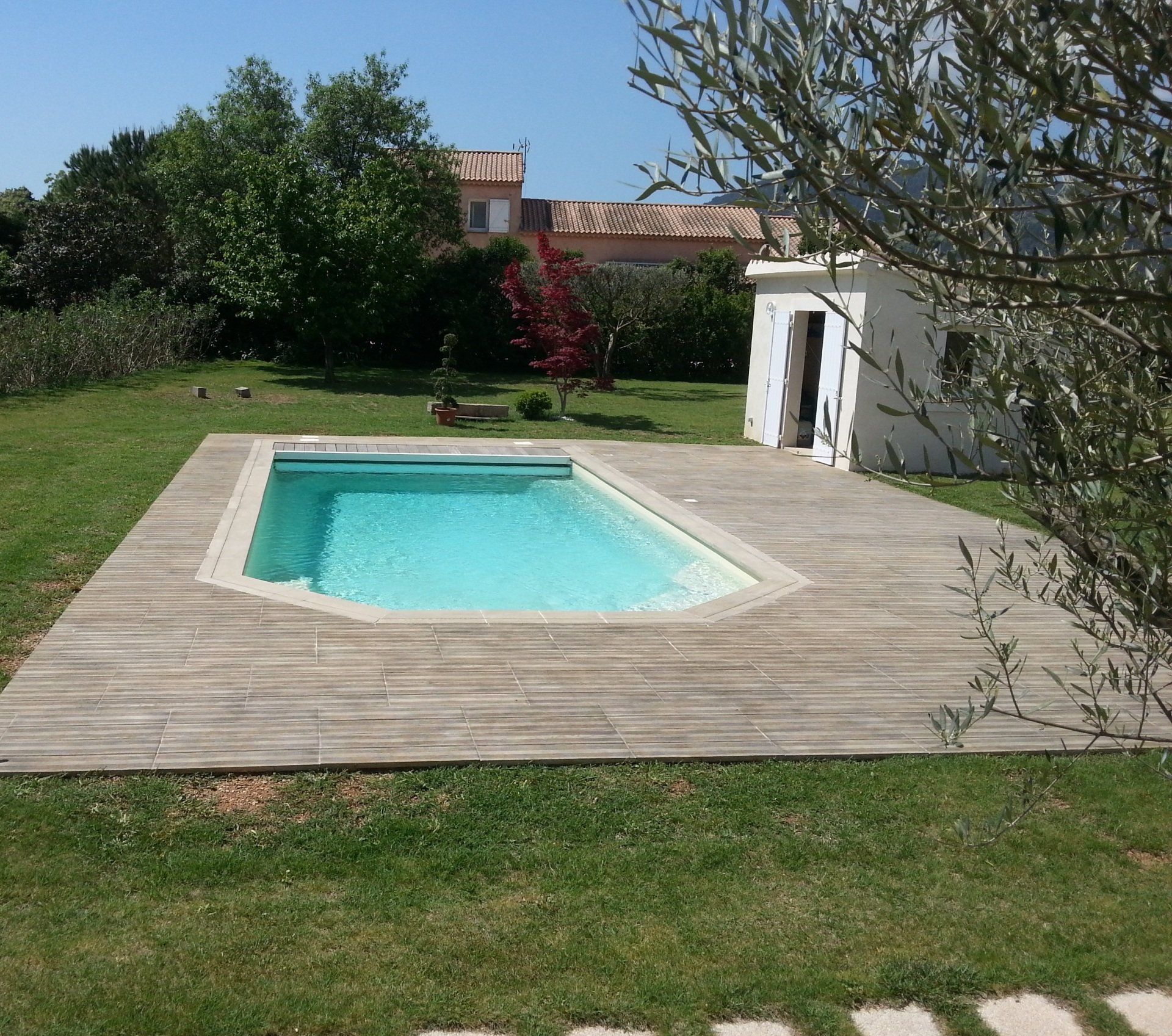 Une terrasse de couleur grise et une maison à côté 