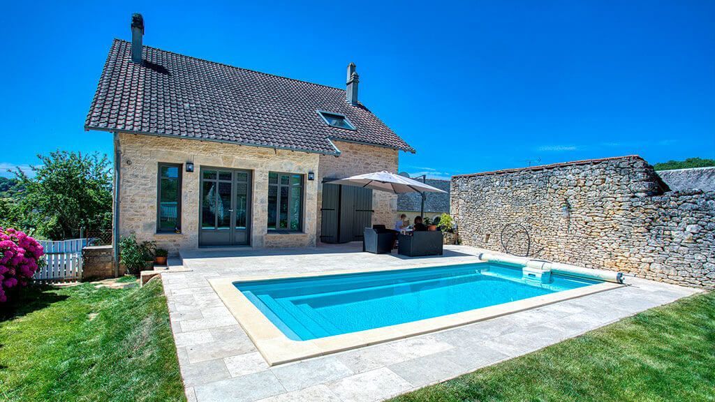 Une maison en pierre avec une piscine et une terrasse