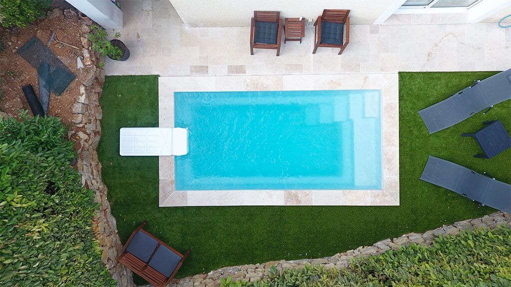 Une petite piscine dans un jardn avec des chaises et dees transats