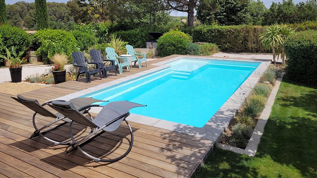 Un jardin avec des transat, une piscine et des arbres