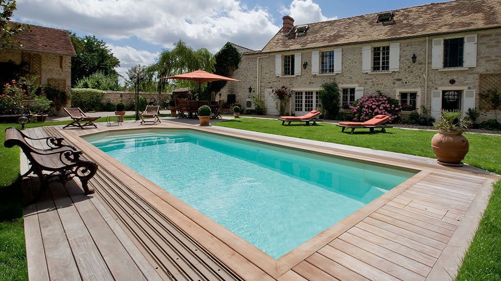 Une grande maison en pierre avec une piscine, des transats et un parasol