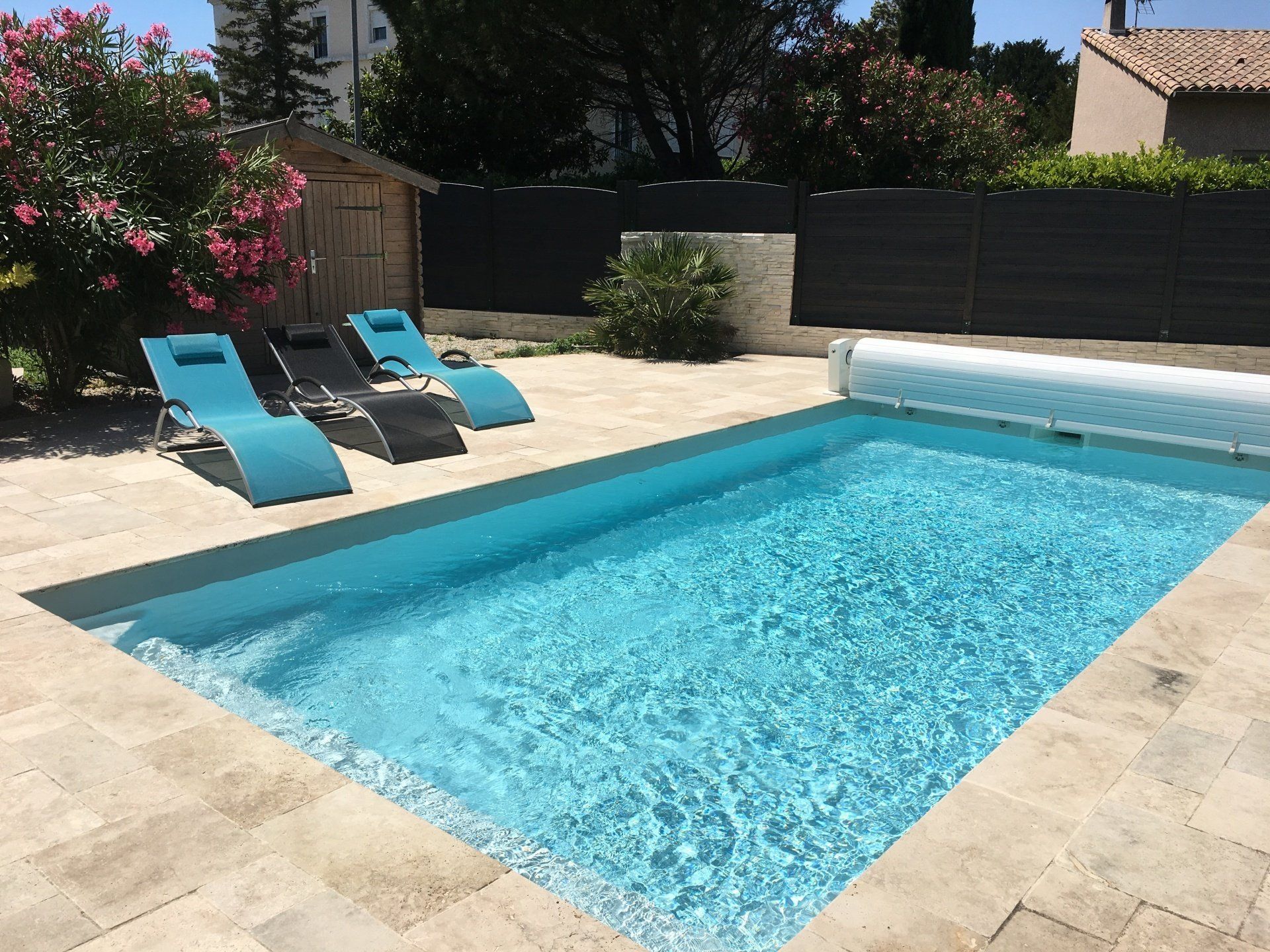 Une piscine avec des transats bleus et une cabane autour