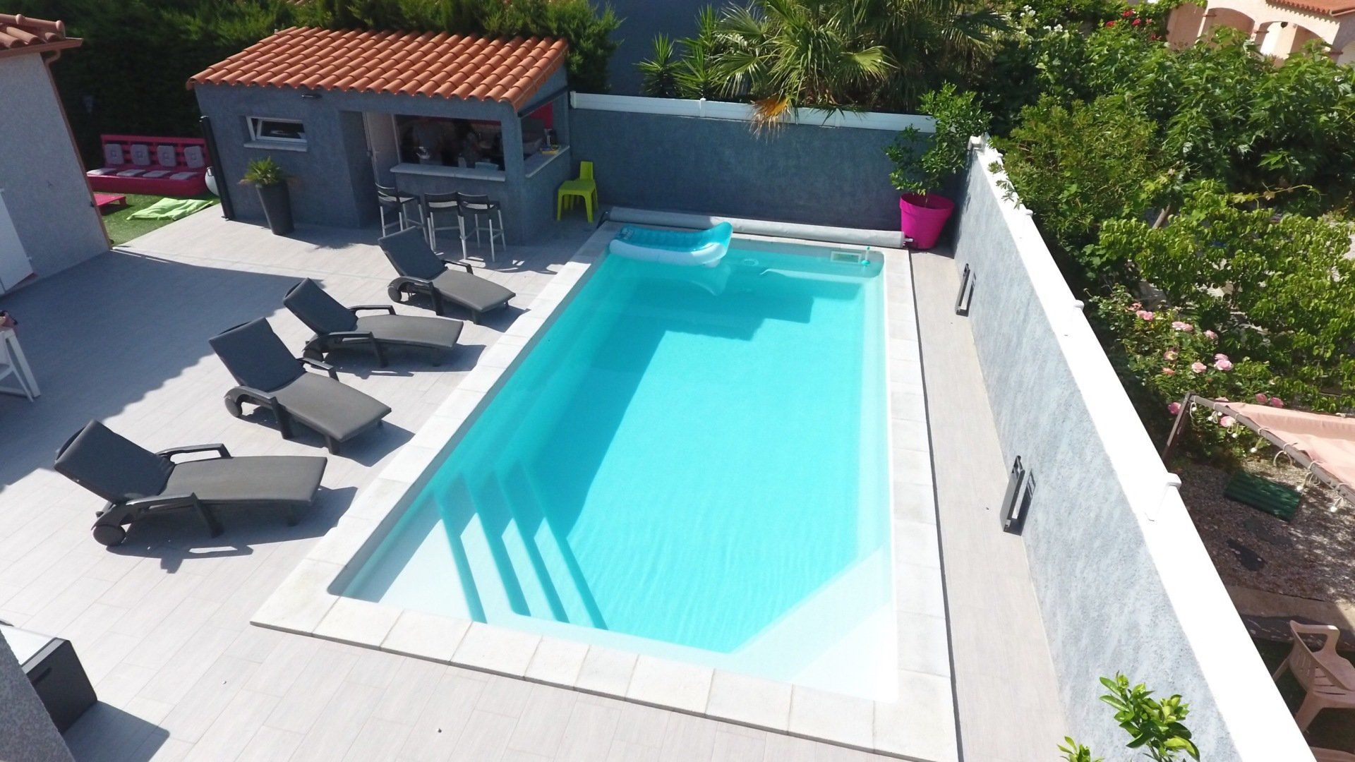Une piscine avec des transats et un abri 