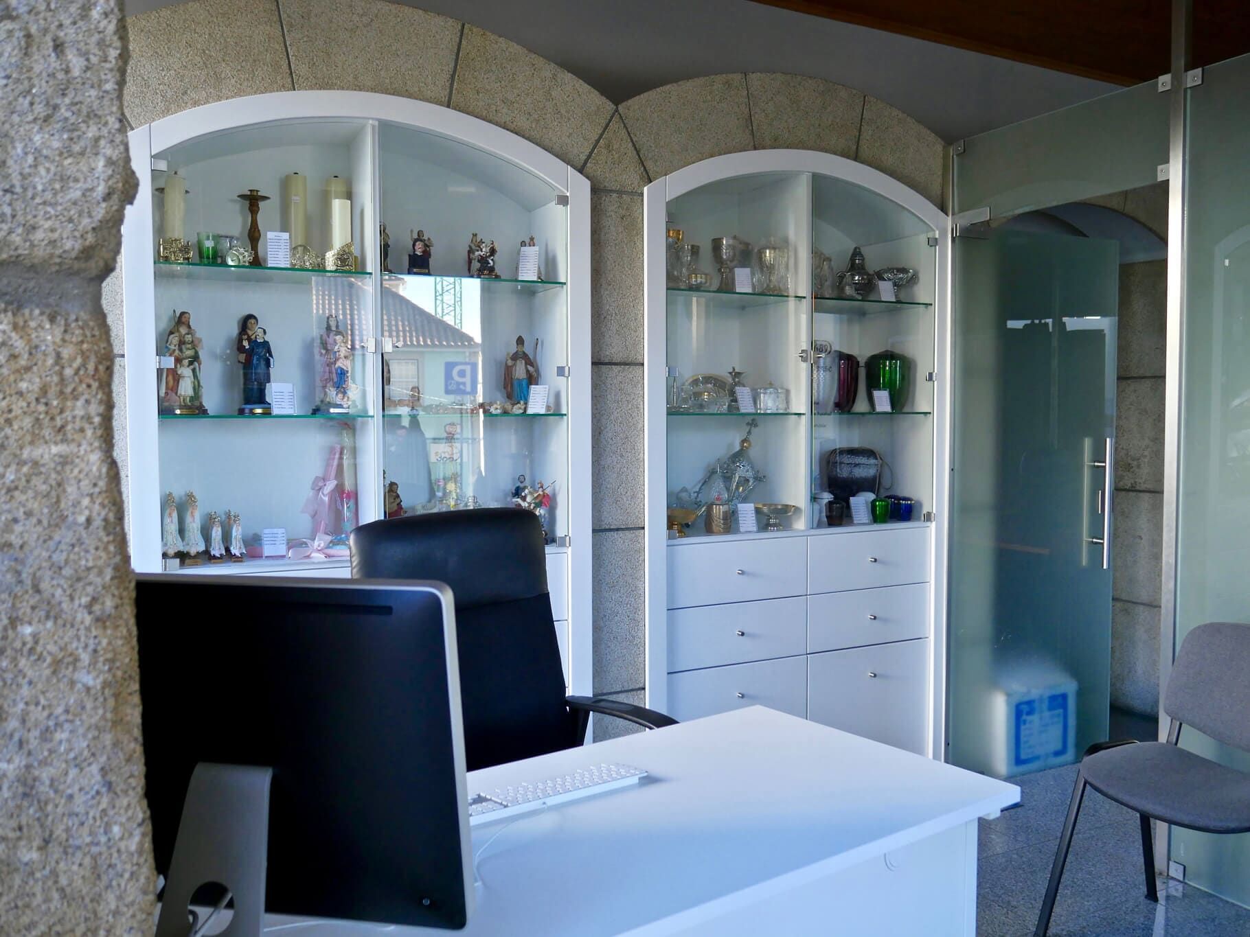 Balcão de recepção com vitrines de vidro contendo itens religiosos.