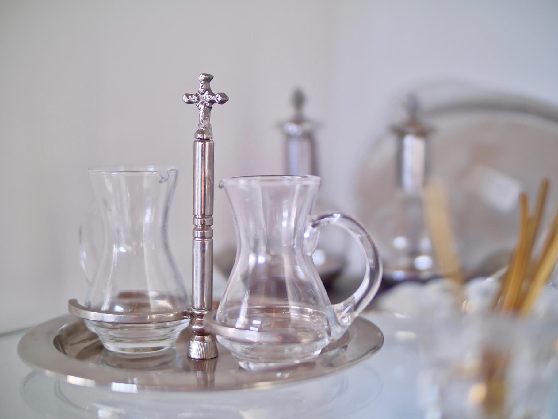 Bandeja de prata com galheteiros de vidro e uma cruz de prata.