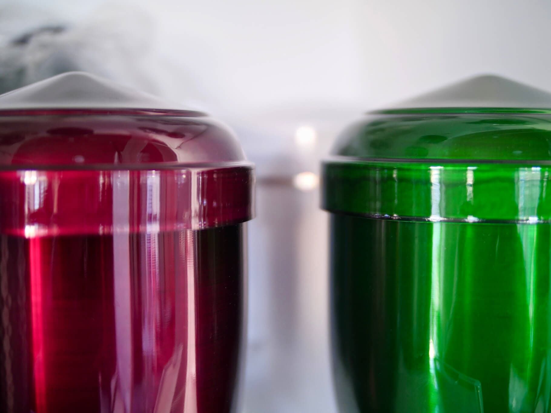 Close de recipientes cilíndricos vermelhos e verdes; possivelmente um dispensador de bebidas congeladas.