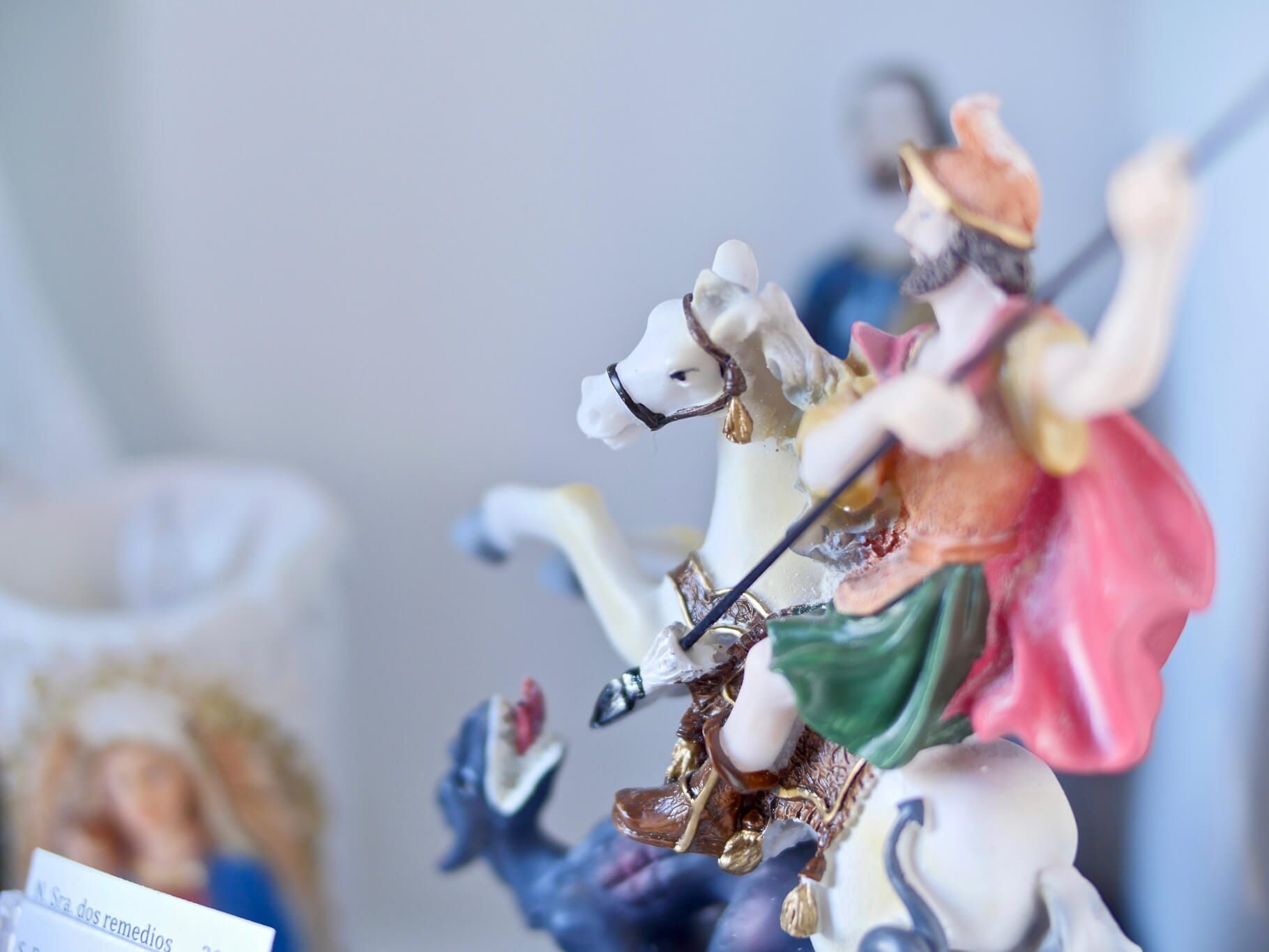 Estátua de São Jorge a cavalo, matando um dragão. A figura é colorida, com uma capa vermelha.